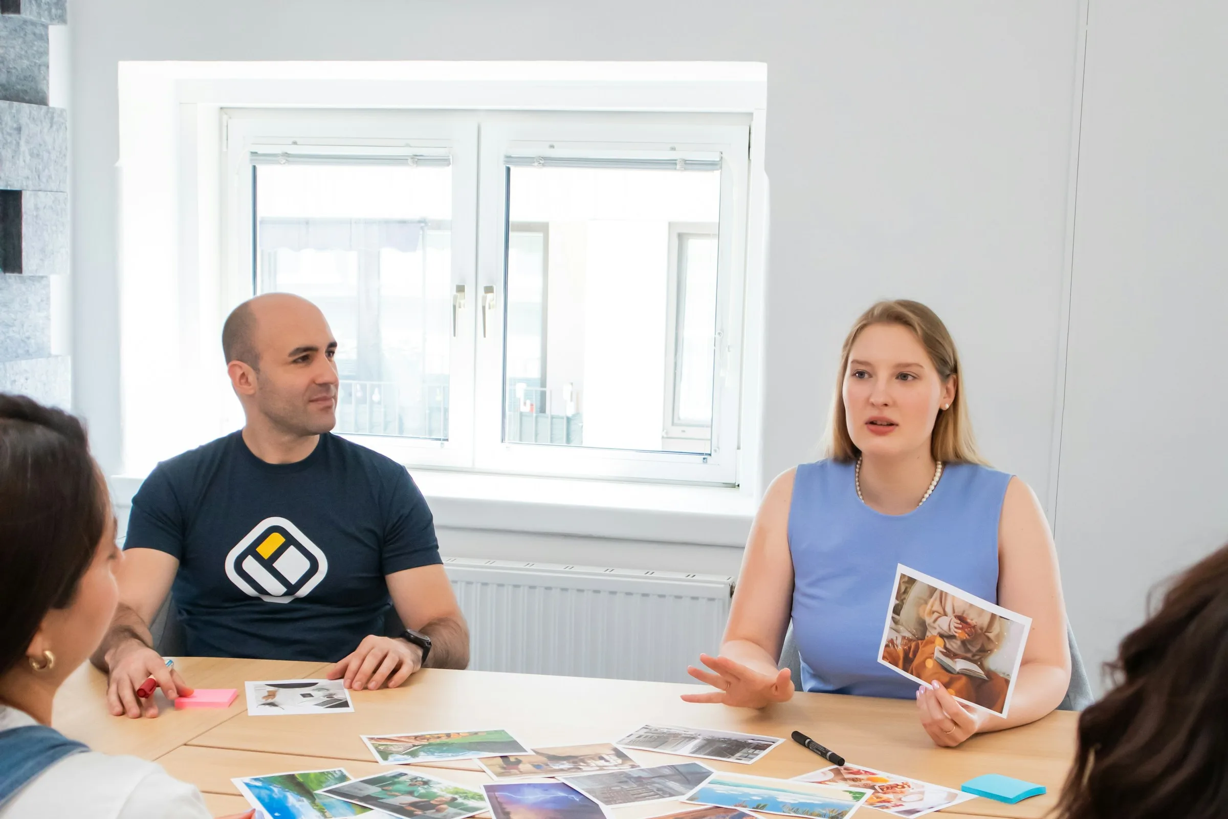 A small group around a workshop table reviewing printed materials together in a bright workspace